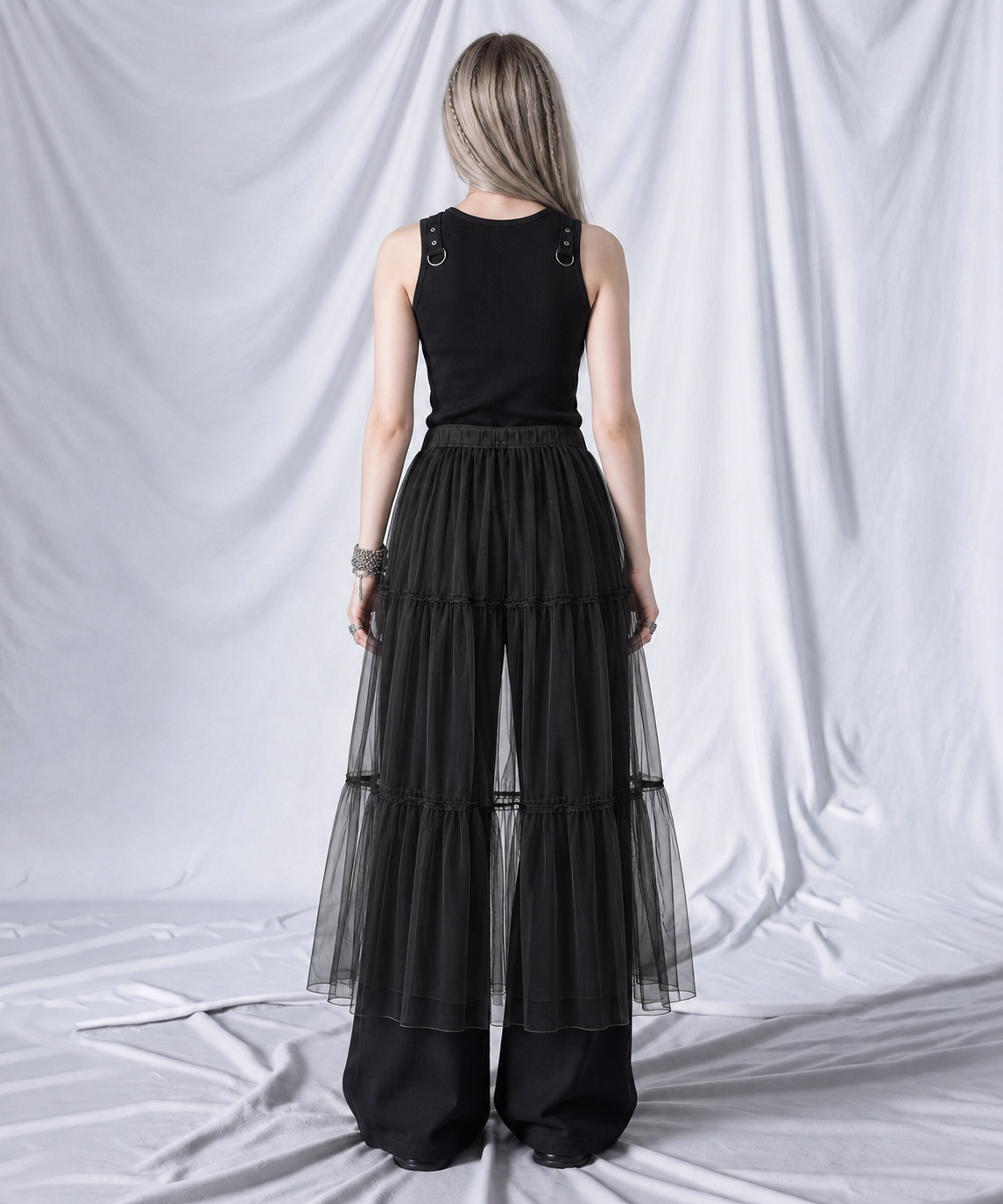Back view of the black layered gauze overlay midi skirt worn over wide-leg trousers.