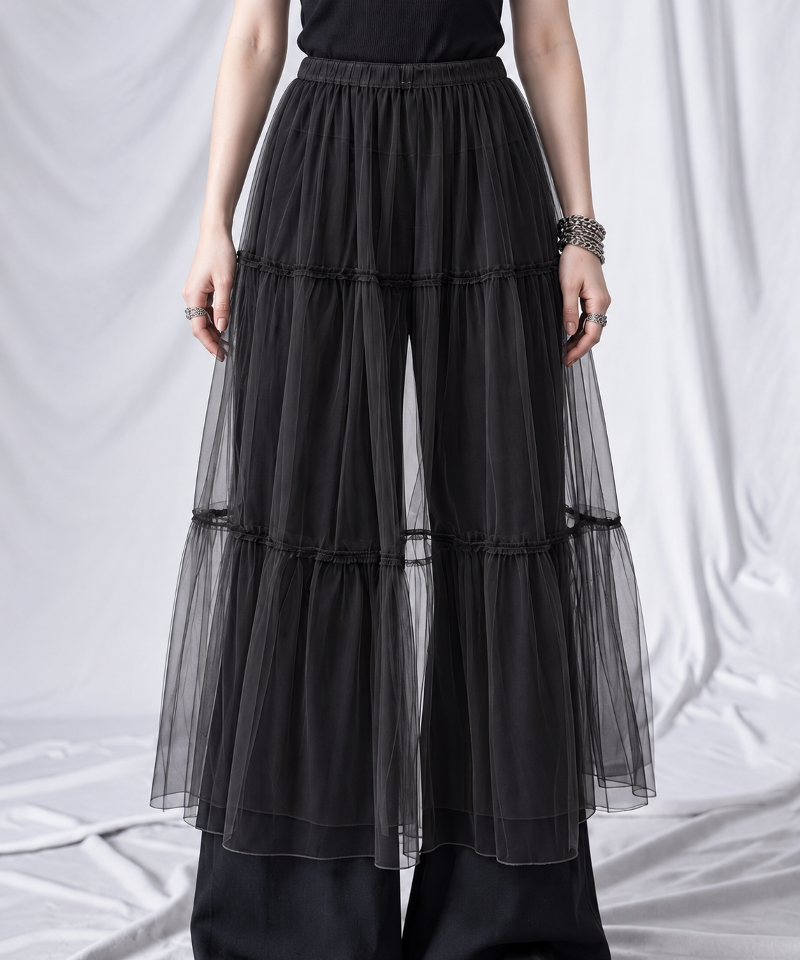 Black gauze overlay skirt close-up showing three sheer tiers, gathered seams and elastic waistband.