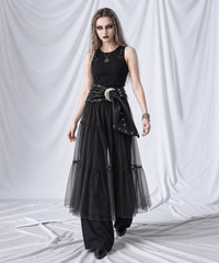 Walking view of the black sheer overlay skirt paired with a silver-buckle wrap belt and black trousers.