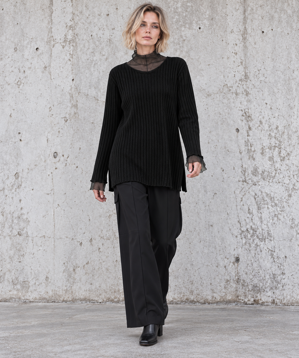 Blonde model walking in black oversized rib-knit sweater and wide-leg black trousers – Simple Moderne