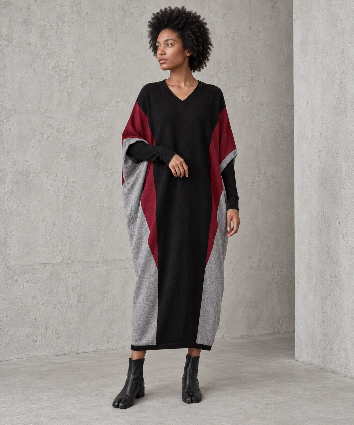 Front view of the black oversized V-neck block knit midi dress with burgundy and heather-grey panels, worn with black tabi boots.