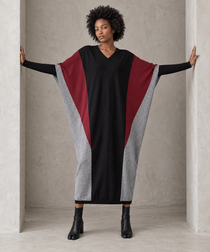 Full-length front view of the black oversized block knit midi dress with arms extended, showing its generous width and tapered hem.
