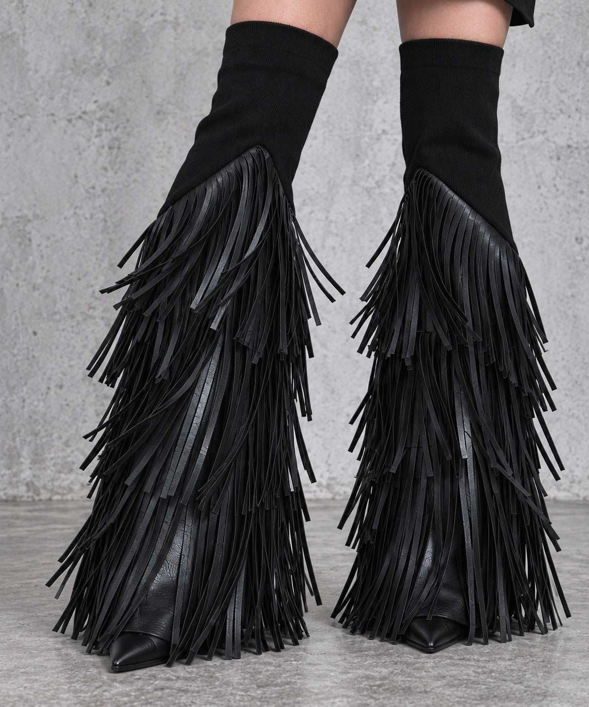 Detail of the fitted black upper cuffs, diagonal fringe attachment and cascading vegan leather tassels on the flared leg warmers.