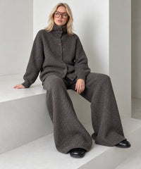 Coffee brown knitted cardigan and wide-leg trousers set on a seated model, showing the relaxed fit and wide legs.