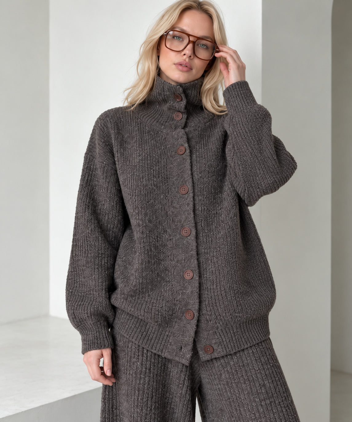 Close-up of the coffee brown knitted cardigan showing its high collar, brown buttons, ribbed cuffs and mélange texture.