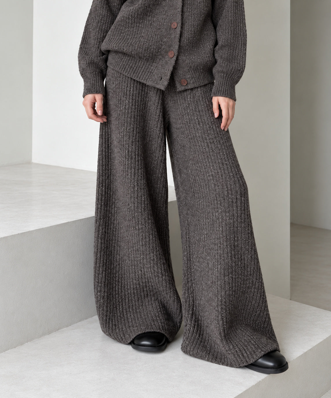 Close-up of the coffee brown wide-leg knitted trousers showing the vertical knit texture, generous drape and full-length hems.
