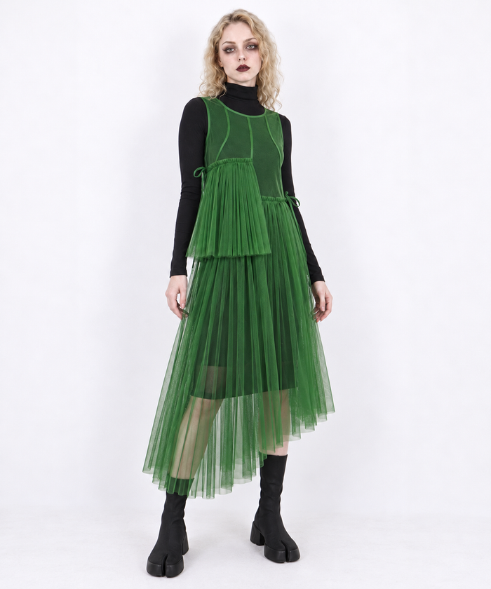 Green mesh asymmetric layered midi dress on a blonde model in a three-quarter view, showing the pleated asymmetric skirt.