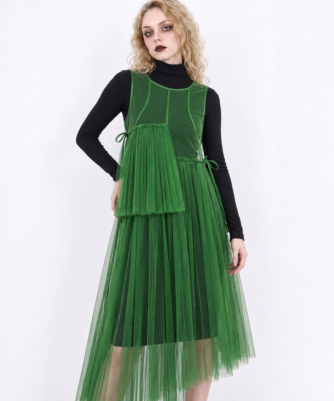 Closer model view of the green mesh dress, showing its round neckline, curved seams and offset pleated panels.