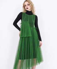Closer model view of the green mesh dress, showing its round neckline, curved seams and offset pleated panels.