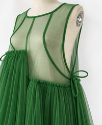 Green mesh dress on a cream mannequin, close-up of the sheer bodice, bound neckline, curved seams and side tie.
