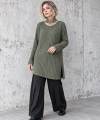 Olive Green Oversized Turtleneck Knit Sweater. Three-quarter front view showing the olive sweater's vertical ribs, side split and sheer cuff extensions.