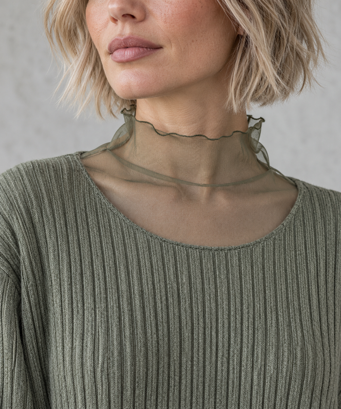 Olive Green Oversized Turtleneck Knit Sweater. Close-up of the sheer olive high neckline with a waved edge above the ribbed sweater's scoop neckline.