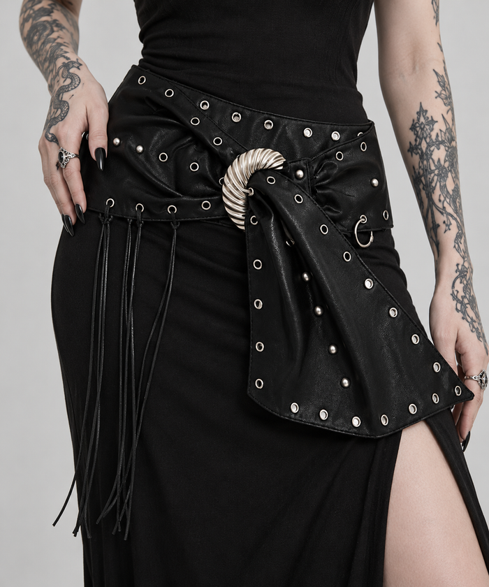 Angled waist close-up of the black Rivet Belt, showing its silver buckle, draped tail, eyelets and thin tassels.