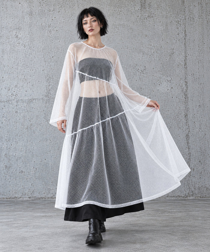 White sheer overlay maxi dress in a stepping pose showing the wide A-line silhouette and diagonal gathered tiers.