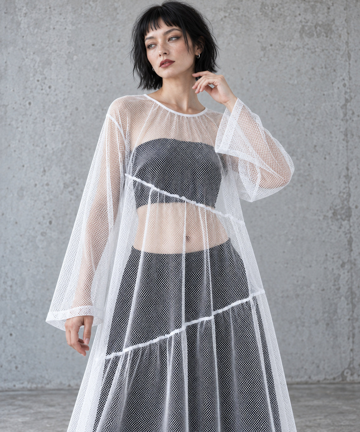 Close view of the white gauze overlay dress showing the round neckline, sheer sleeves and diagonal seams over black separates.