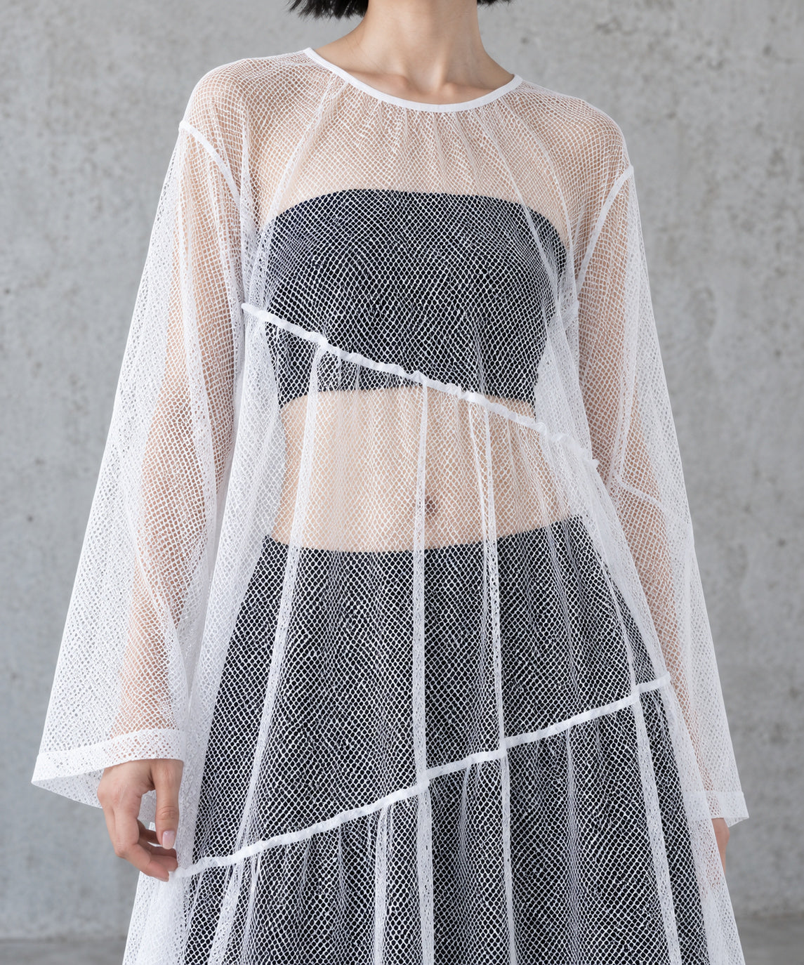 Detail of the white diamond mesh, gathered tier seams and bound neckline of the layered gauze maxi dress.